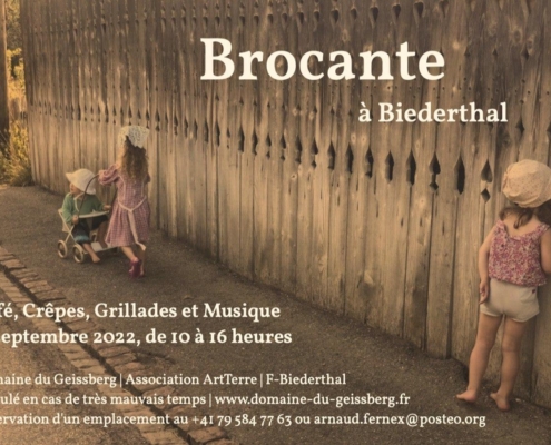 Enfants en tenue vintage près d'une clôture en bois à la ferme du Geissberg à Biederthal, agriculture biodynamique en circuit court au cœur de la nature alsacienne.