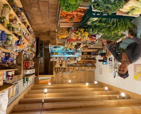 Intérieur d'une épicerie de la ferme du Geissberg à Biederthal, avec des produits frais issus de l'agriculture biodynamique disposés en rayon et un vendeur en circuit court derrière le comptoir.