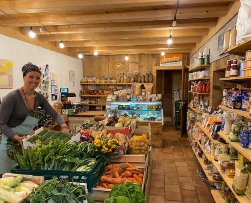 Intérieur d'une épicerie de la ferme du Geissberg à Biederthal, avec des produits frais issus de l'agriculture biodynamique disposés en rayon et un vendeur en circuit court derrière le comptoir.