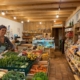 Intérieur d'une épicerie de la ferme du Geissberg à Biederthal, avec des produits frais issus de l'agriculture biodynamique disposés en rayon et un vendeur en circuit court derrière le comptoir.